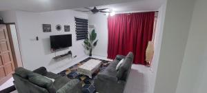 Nur Homestay Residensi Afamosa mslim guest only في Kampong Alor Gajah: غرفة معيشة مع أريكة وستارة حمراء