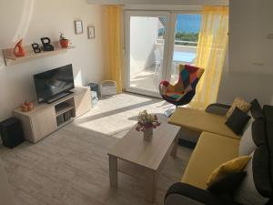 a living room with a couch and a tv and a table at Apartments Lucie in Biograd na Moru