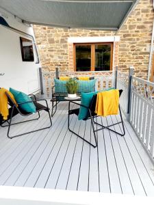 un porche con 2 sillas y una mesa en una terraza en Caravane tractable, en Paliseul
