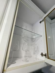 vier wijnglazen op een plank in een kast bij Lovely 2-bed 20 mins to central London in Londen