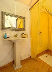 a bathroom with a sink and a mirror at Erg Lihoudi Luxury desert camp with Camel ride, meals & sandboarding in Boumalne
