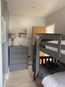 a bedroom with two bunk beds and a night stand at The Annexe Porthcawl Pet Friendly 2 Bedroom Flat with King Size bed bunk beds and sofa bed sleeps up to 5 people in Nottage