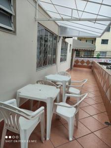 eine Terrasse mit weißen Tischen und Stühlen auf dem Balkon in der Unterkunft Apartamento em Balneário Camboriú centro,quadra mar in Balneário Camboriú