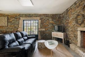 uma sala de estar com um sofá de couro e uma parede de pedra em R3 Service - Casula no Caramulo em Tondela