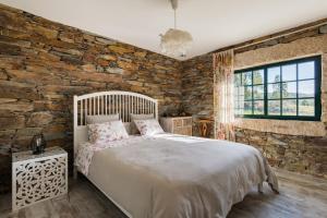 a bedroom with a stone wall and a large bed at R3 Service - Casula no Caramulo in Tondela