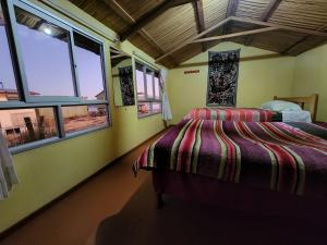 a bedroom with a bed in a room with windows at Hanan Pacha Lodge in Puno