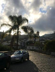 une voiture garée dans une rue pavée avec un palmier dans l'établissement Pouso Ponte dos Suspiros com Garagem, à Ouro Preto