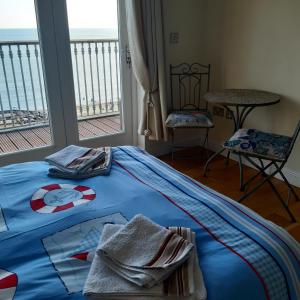 een slaapkamer met een blauw bed en handdoeken bij Kaia Penthouse, waking up to the sound and smell of the ocean in Ventnor