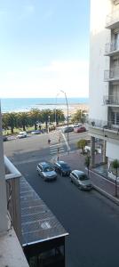 Departamento vista al mar Playa Las Toscas في مار ديل بلاتا: شارع فيه سيارات تقف في موقف بجانب مبنى