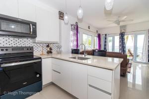 a kitchen with white cabinets and a black stove top oven at THE SPLASHING VIEW in St Mary