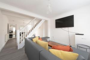 a living room with a gray couch and a tv at Beautiful 2 bed house in Grays 4 separate beds sleeps 5 in Grays Thurrock