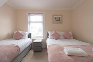 una camera con due letti con cuscini rosa e una finestra di Beautiful 2 bed house in Grays 4 separate beds sleeps 5 a Grays Thurrock