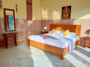 a bedroom with a large bed with a headboard at Alamku Bungalow in Tirtagangga