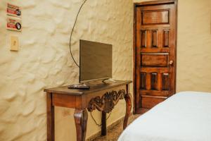 a wooden table with a monitor on it next to a bed at Hotel Condesa in Comayagua