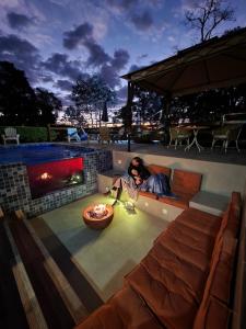 a person sitting on a couch next to a fireplace at Hortensias Pousada Boutique - Piscina Aquecida 37 Graus e Fire Pit a Gas in Monte Verde