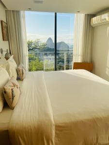 um quarto com uma cama branca e uma grande janela em Pousada Rio144 no Rio de Janeiro