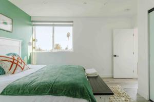 a bedroom with a bed with a green blanket and a window at Stunning Hollywood Townhouse with Sunny views in Los Angeles