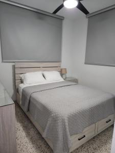 a white bedroom with a large bed and a light at Cozy apartment in the heart of the city in Ponce