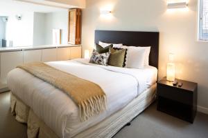 1 dormitorio con 1 cama grande con sábanas y almohadas blancas en QS Jade, en Queenstown