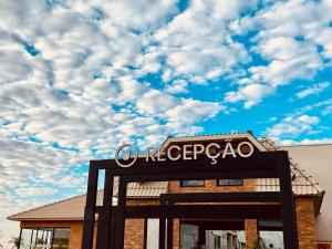 a sign in front of a building with a cloudy sky at Royal Tulip Holambra in Holambra