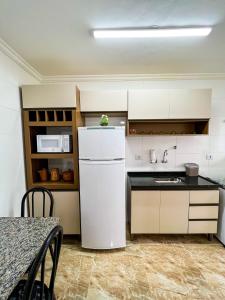 a kitchen with a white refrigerator and a table at Frente para o Mar com Vista Incrível - Porto1003 in Praia Grande