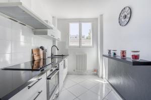 una cocina blanca con reloj en la pared en Détente et Confort proche Paris et Orly, en Choisy-le-Roi