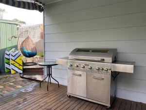a grill on a patio with a table and a stool at Invy Escape in Inverloch