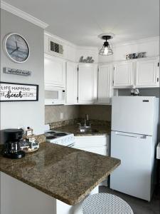a kitchen with white cabinets and a white refrigerator at Sea Chase with an ocean view at Casa Del Mar in Galveston