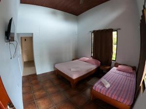 Cette petite chambre comprend 2 lits et une fenêtre. dans l'établissement Laureles Collection Uvita - Cabinas Los Laureles, à Uvita