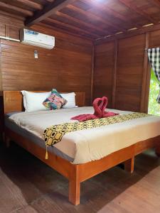 Una cama con dos toallas rojas encima. en Bulian Homestay, en Kubutambahan