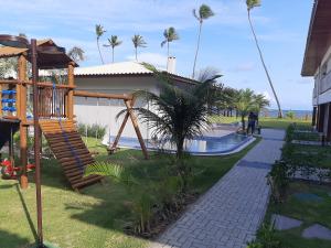 a playground in front of a house with palm trees at Itacimirim - Duplex Aconchegante, Pé na Areia in Itacimirim