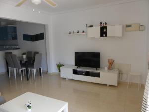 a white living room with a television and a table at Bungalow moderno luminoso terraza solarium patio - PISCINA COMUNITARIA in Puerto Marino