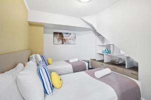 sypialnia z 2 łóżkami i schodami w obiekcie Lorne Beachfront Accommodation w mieście Lorne