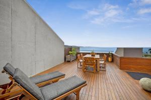 a deck with chairs and a table on a balcony at Lorne Beachfront Accommodation in Lorne