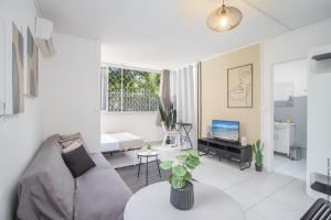 un soggiorno con un divano e una TV di Studio La Pivoine, en bord de mer a Les Trois-Îlets