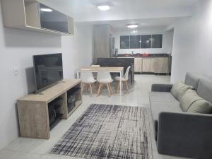 Una sala de estar con un sofá, un televisor y una mesa. en Casa do Bosque 87, en Gramado
