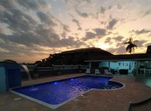 a swimming pool with a sunset in the background at Chácara Atibaia in Atibaia