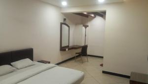 1 dormitorio con cama y espejo en la pared en Ashok Bhavan, en Madurai