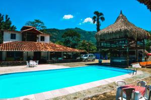 a swimming pool in front of a house with a thatch roof at Hotel Hacienda la Bonita in Amagá