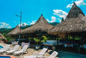 eine Gruppe Stühle und Strohschirme in einem Resort in der Unterkunft Hotel Hacienda la Bonita in Amagá