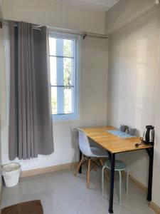 een kamer met een houten tafel en een raam bij Baan Nukanong Guesthouse in Chiang Rai