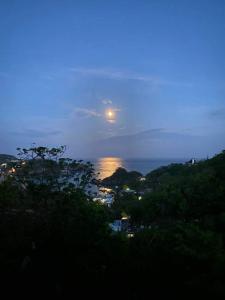 Una luna llena elevándose sobre una ciudad por la noche en Casa Sakal en Puerto Ángel
