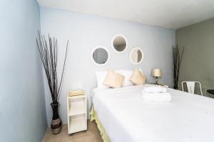 1 dormitorio con 1 cama blanca grande con espejos en la pared en Skyline Suites 2 Queen bedroom condo en Montego Bay