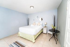 1 dormitorio con 1 cama blanca y 2 espejos en Skyline Suites 2 Queen bedroom condo en Montego Bay