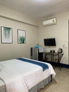 a bedroom with a bed and a desk and a television at Baan Nukanong Guesthouse in Chiang Rai