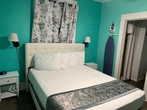 a bedroom with a white bed with blue walls at Americas Best Value Inn Royal Carriage in Jamestown