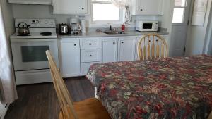 cocina con armarios blancos, mesa, mesa y sillas en L'escale du routard en Alma
