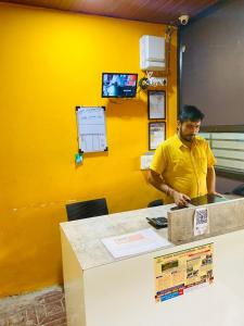 a man standing at a counter in a yellow room at sonai POWERED BY PEACEFUL STUDIO in Panvel