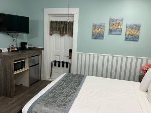 Dormitorio con cama, escritorio y TV en Americas Best Value Inn Royal Carriage, en Jamestown