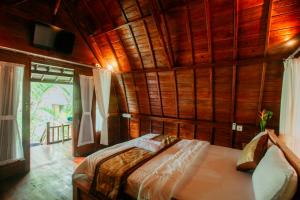 a bedroom with a bed in a room with wooden walls at Ita House in Tegalalang